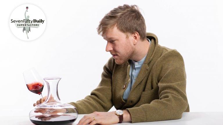 Collin Wagner closely inspects a glass of red wine