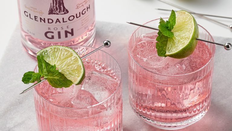 Pale pink spirit on the rocks garnished with lime and mint.