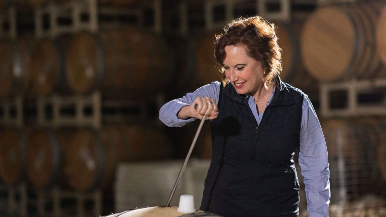 Kristen Barnhisel dips a wine thief into a barrel in the cellar.