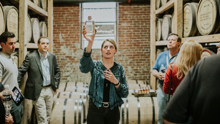A tour guide shows off a sample bottle to a booze trail tour group