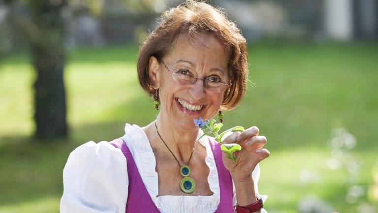 A woman holds up a plant sprig