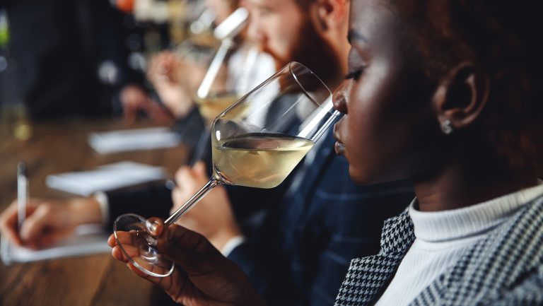 African woman sommelier bartender smelling white wine and making degustation card