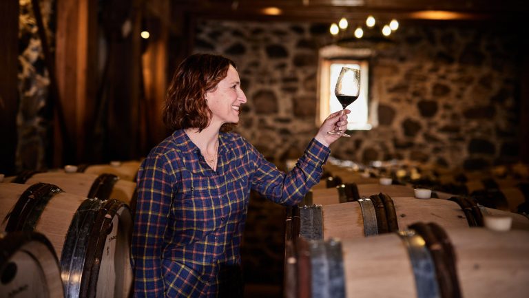 Nicole Marchesi poses in a cellar as she examines a glass of wine