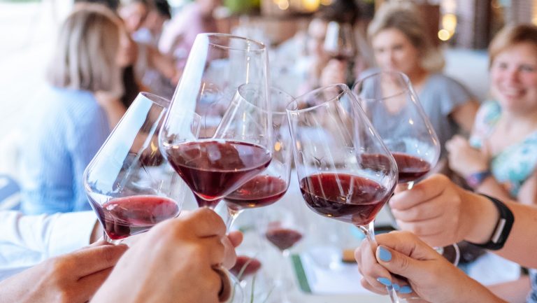 Multiple people clink wine glasses filled with Beaujolais wines