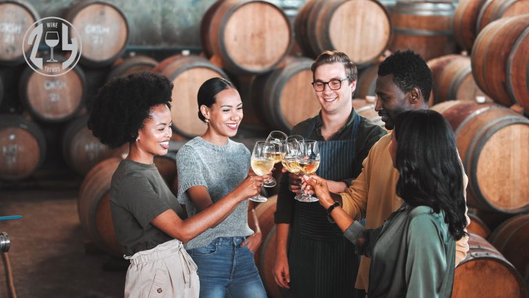 A group of wine enthusiasts clink wine glasses in a room full of wine barrels. A SevenFifty Daily 2024 Trends stamp is in the top left corner.