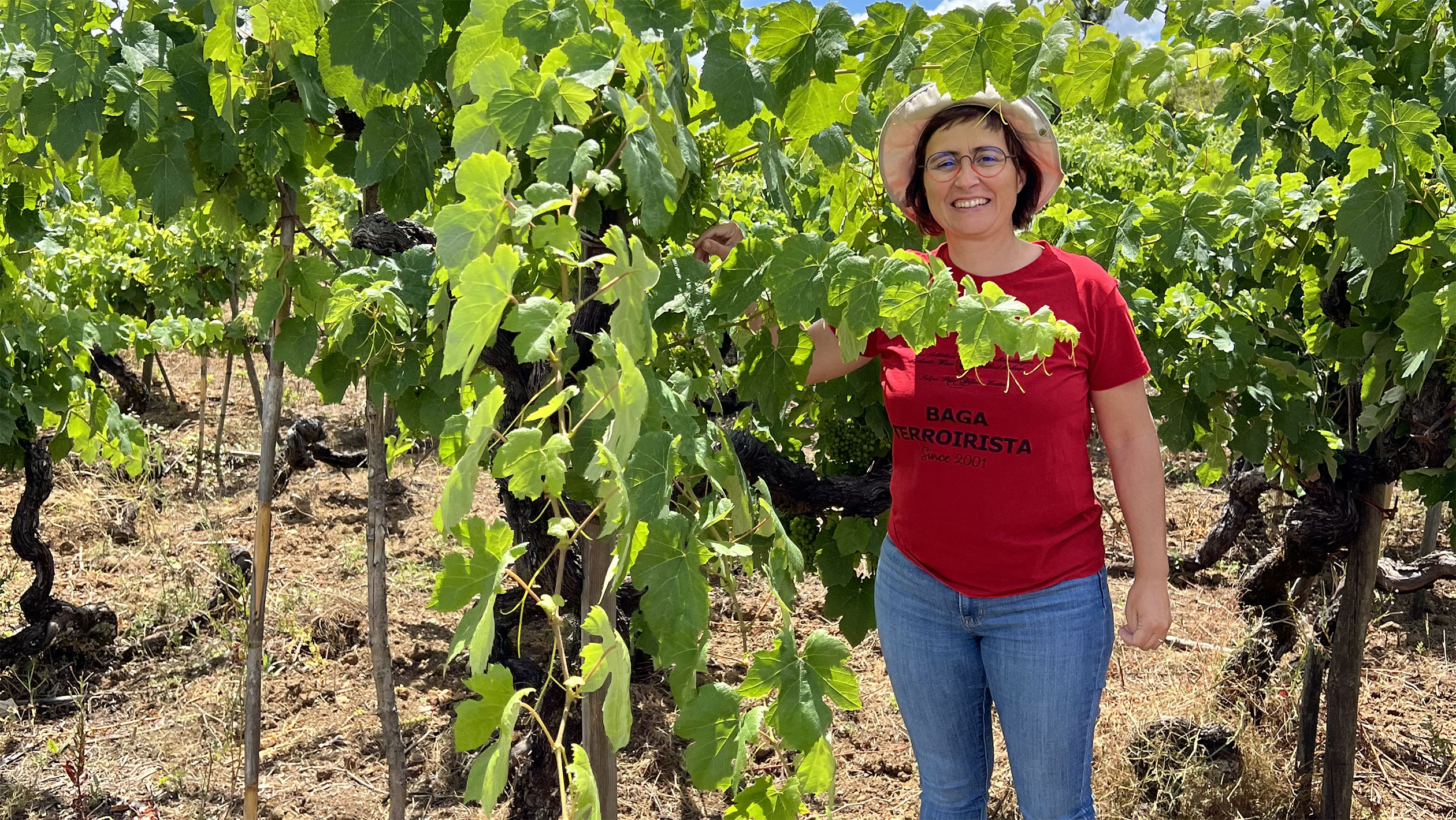 Headshot of Filipa Pato who poses amongst the grapes in a vineyard.