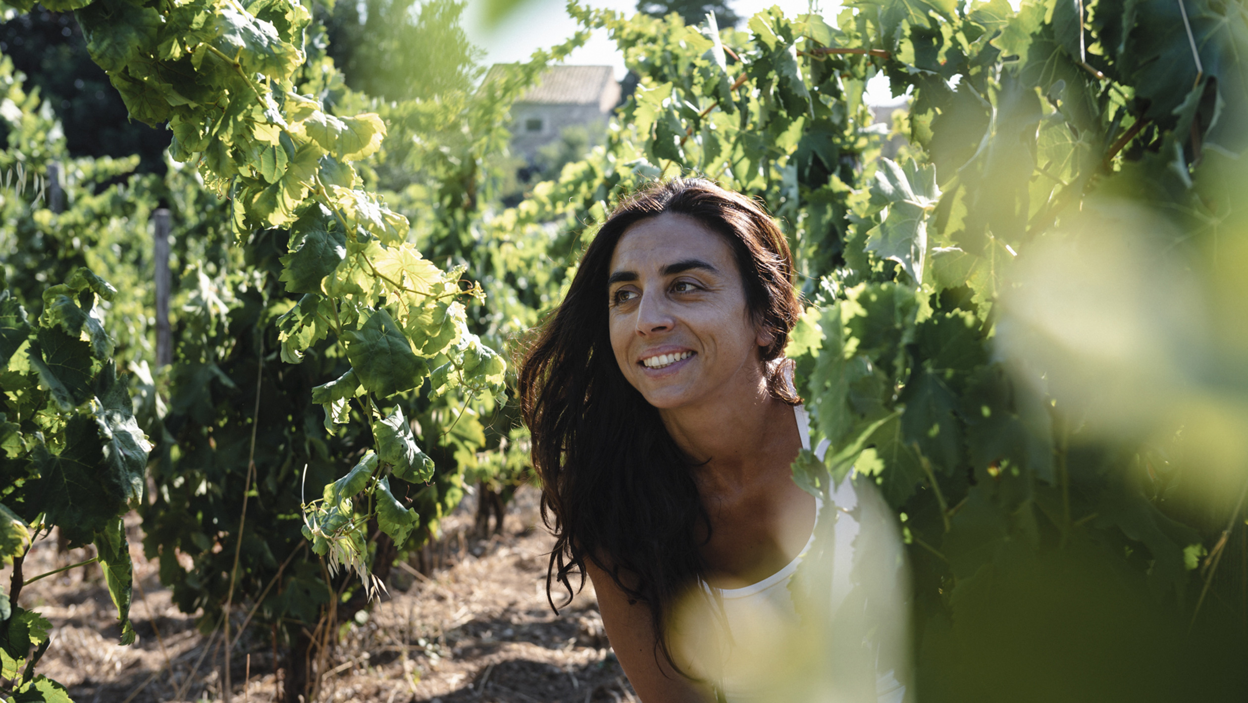 Arianna Occhipinti poses amongst the vines of a vineyard on a sunny day