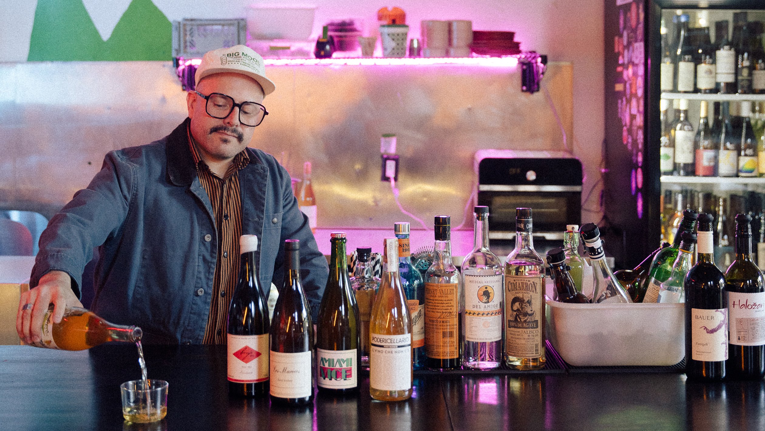 Richard Garcia poses behind a bar laid with bottles
