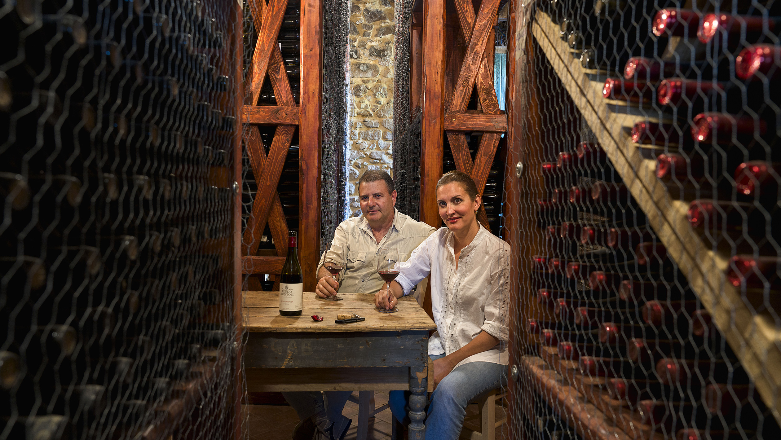 Fabio Sireci and Melissa Muller pose in a wine cellar at a table