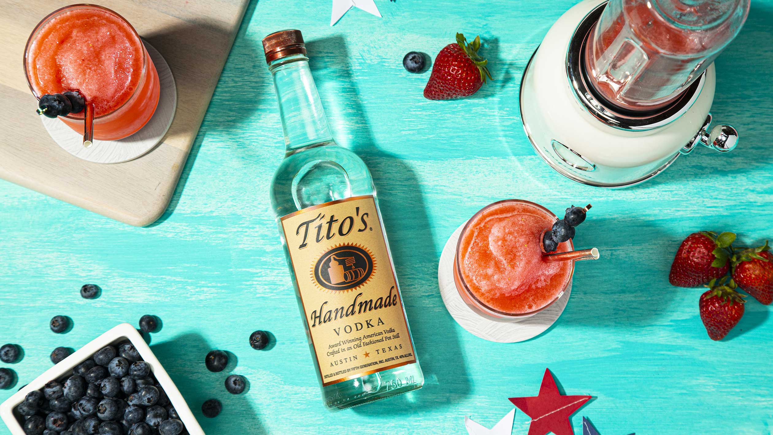 A bottle of Tito's Vodka amongst an display of summer fruits and beverages 