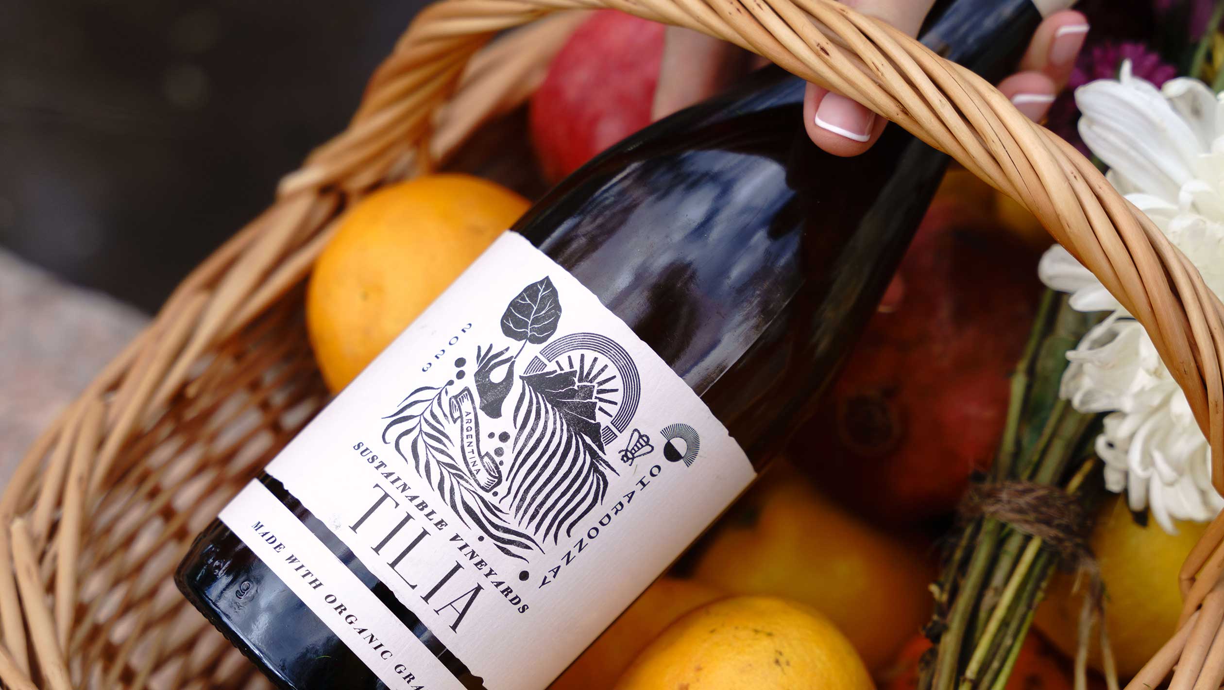 A bottle of TILIA wine atop a basket of fresh fruit