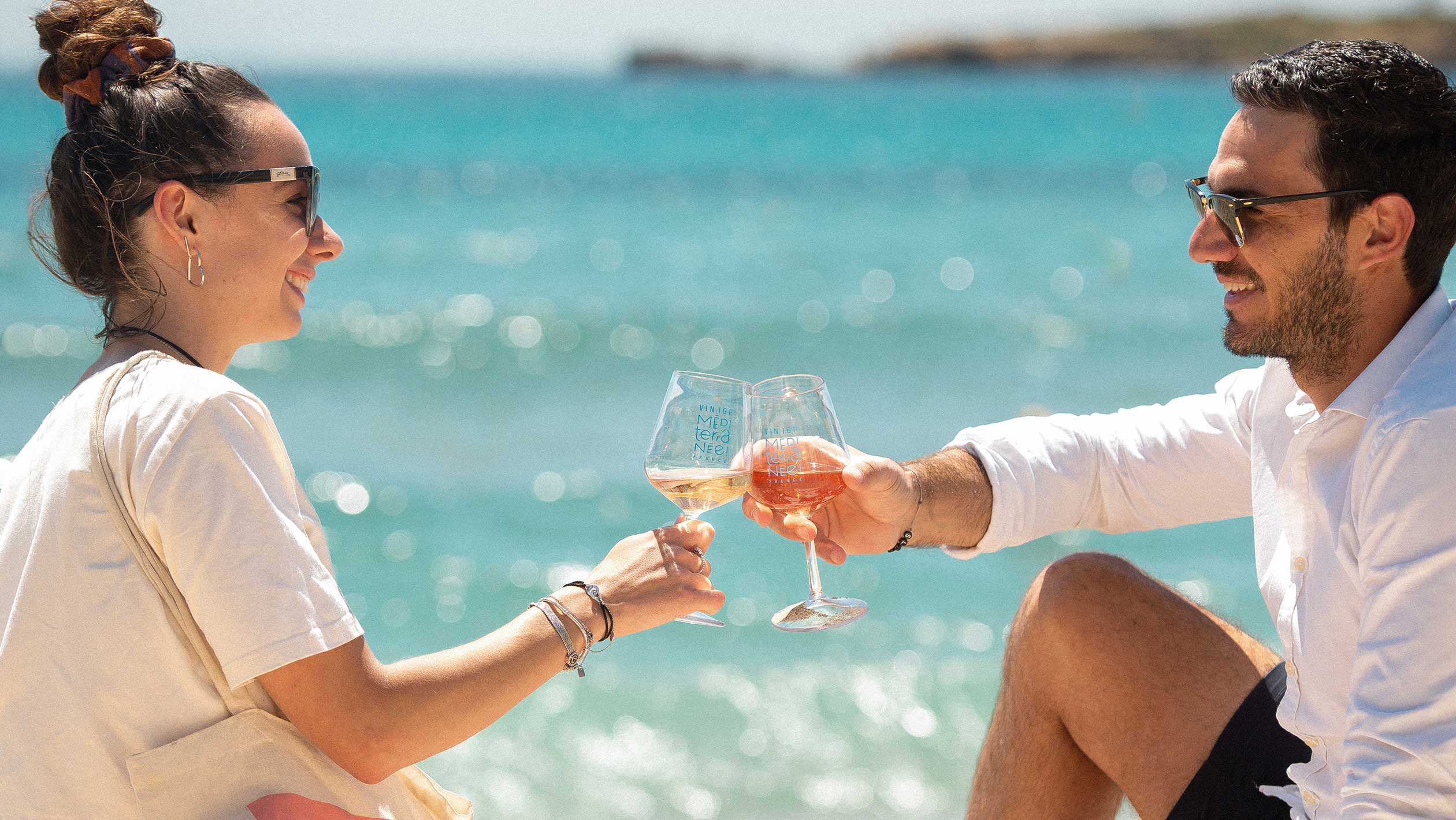 A couple enjoys a glass of rosé on the beach