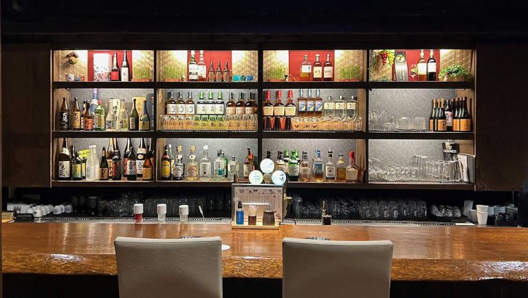 A bar with a number of shelves bearing liquor bottles