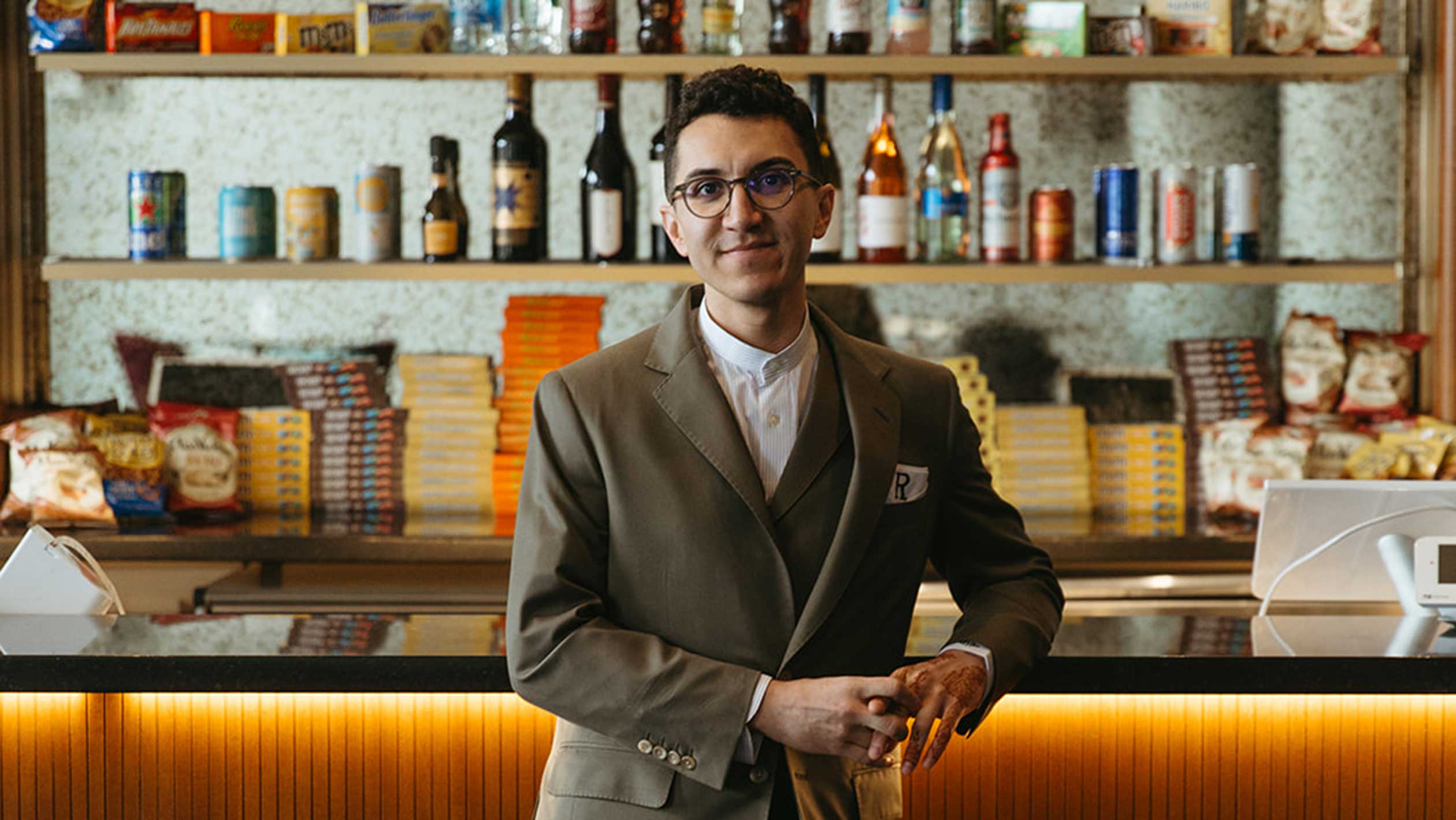 A headshot of Tony Rivera posing in front of a bar.