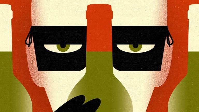 Masked man peering behind a bottle of wine