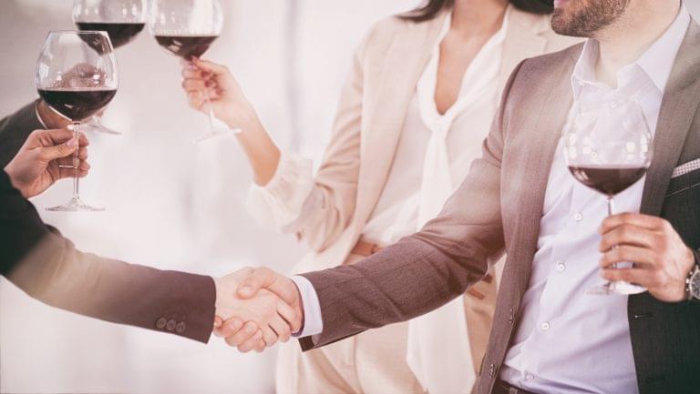 people shaking hands and drinking wine