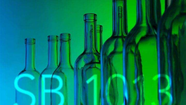 A row of empty bottles sits in front of a projection screen that shows "SB 1013."