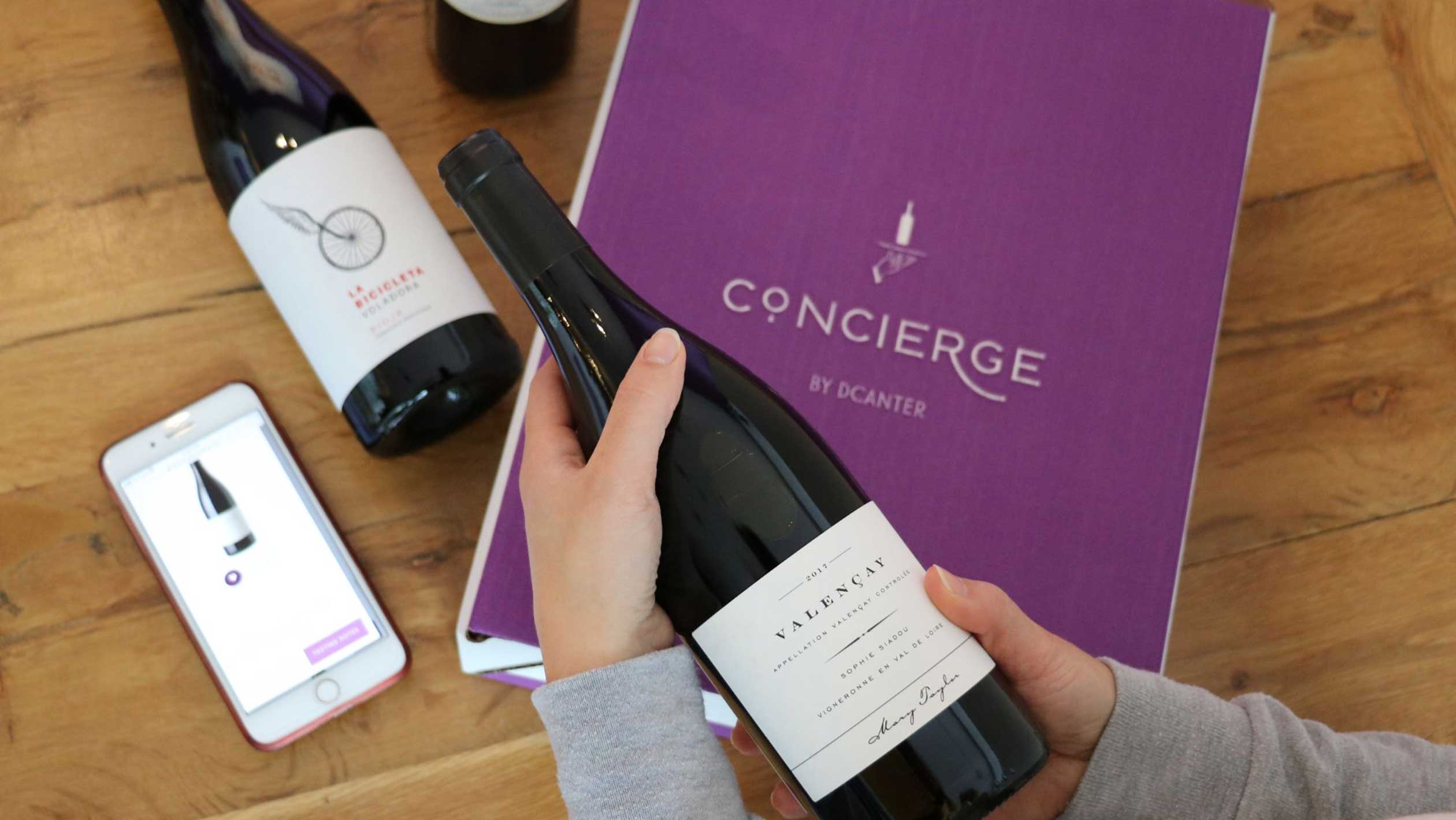 A marketing image from DCanter showing a client unboxing a Concierge wine box