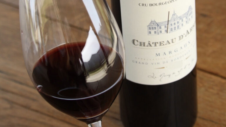 A photo of Château d'Arsac wine bottle with wine in glass.