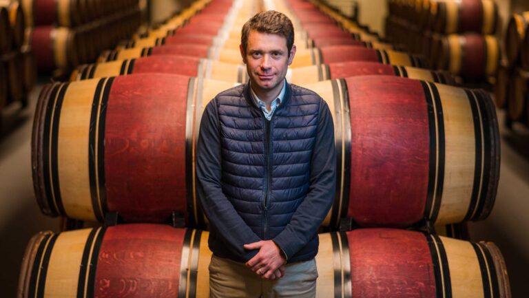 A photo of Vincent Decup in front of barrels in a cellar.