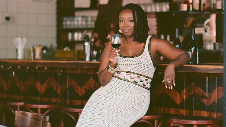 Sommelier Cha McCoy at the bar with a glass of wine.
