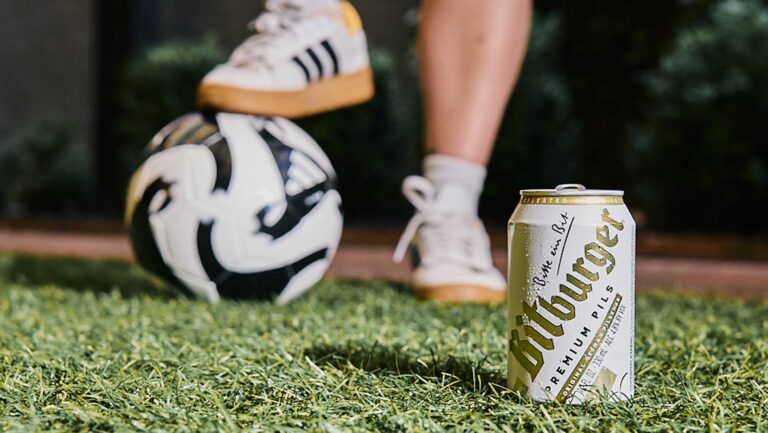 A soccer ball underfoot next to a can of Bitburger pilsner.